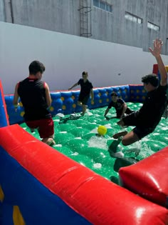 several people playing in an inflatable pool with balls and frisbees