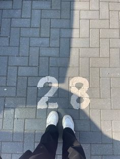 someone is standing on the sidewalk with their feet up and number 28 painted on it