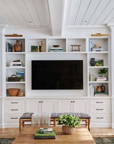 a living room with white bookcases and a flat screen tv on the wall