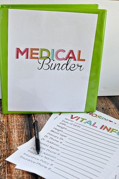 a medical binder sitting on top of a wooden table next to a pen and paper