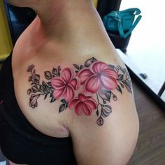 a woman's chest with flowers and leaves tattooed on the side of her body