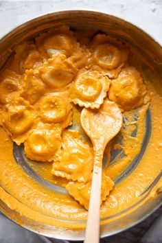 a wooden spoon is in a bowl filled with dumplings and sauces on a marble table