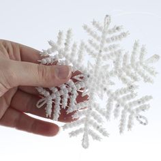 a hand holding a snowflake in front of a white background