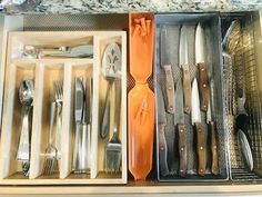 an open drawer with silverware and utensils in it's trays