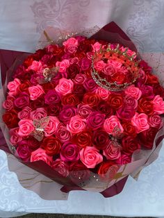 a large bouquet of pink and red roses with tiara on top in a box