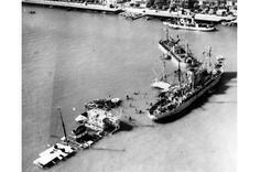 an old black and white photo of ships docked in the water with buildings in the background