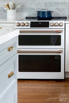 a white stove top oven sitting inside of a kitchen next to a wooden countertop