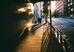 people are walking down the street at sunset