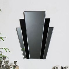 a mirror mounted to the side of a white wall next to a vase with flowers