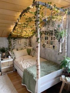 a white bed sitting under a canopy covered in plants and string lights next to a small table