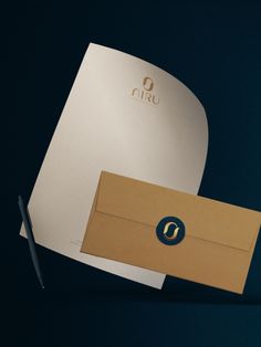 an open envelope with a pen next to it on a black background, and the letter o is in gold