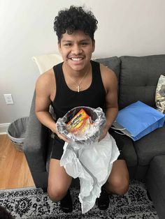 a man sitting on a couch holding a bag of chips and wrapped in tissue paper