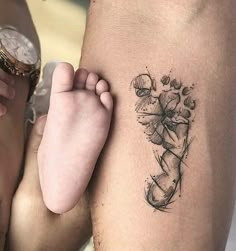 a person with a tattoo on their arm holding a baby's foot and looking at the camera