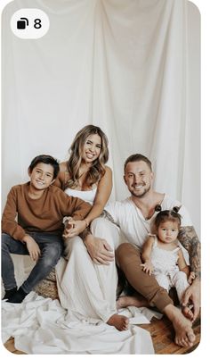 a man, woman and two children are posing for a family photo in front of a white backdrop