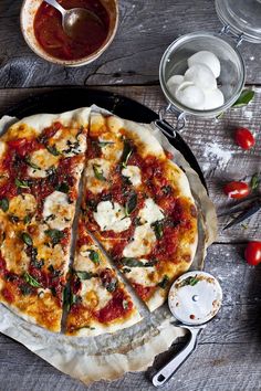 a pizza sitting on top of a pan covered in cheese and sauce next to tomatoes