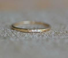 a gold wedding band with three diamonds on it sitting on a carpeted surface in front of the camera