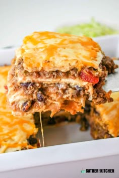 lasagna casserole with meat and cheese is being lifted from the casserole dish