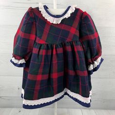 There are two of these dresses, perfect for twins, friends or family! Long sleeve plaid dress in red, navy & green. Unique style lace and navy blue trim along neckline, hem and sleeves. Three button closures on the back. Size: 18 months Measurements (approximate): Shoulder to Hem: 16" Armpit to Armpit: 12" Brand: BeBe d'amour Condition: Some red bleeding on the white lace hem and collar. See pictures for details. Be sure to check out my shop! New items added often! https://www.etsy.com/shop/AutumnRoseArtVintage Plaid Dresses For Fall Holiday, Plaid Cotton Dress For Winter, Plaid Dress For Christmas Holiday, Plaid Christmas Holiday Dress, Red Cotton Dresses With Doll Collar, Baby Tartan Dress, Long Sleeve Plaid Dress, Christmas Plaid Dress Baby, Green Long Sleeve Dress