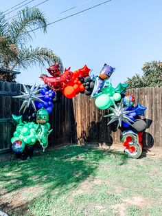 some balloons that are in the shape of animals on a lawn near a wooden fence