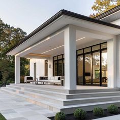 a modern house with white walls and black trim on the front porch, covered in glass doors