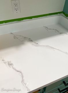 the counter top is being painted white with green trim and some electrical wires on it