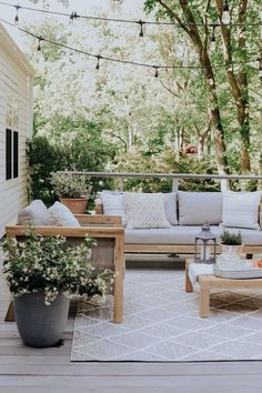 an outdoor living area with couches, tables and potted plants on the deck