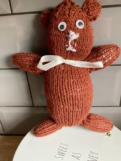 a knitted teddy bear sitting on top of a toilet