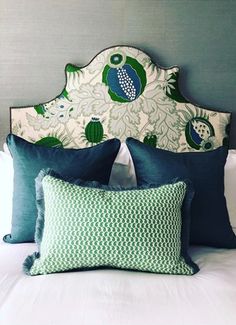 a bed with blue and green pillows on it's headboard in a bedroom