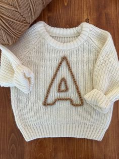 a white sweater with a triangle drawn on it and a ball of yarn next to it