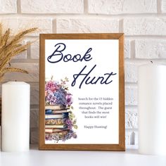 a book hunt sign sitting next to some candles and books on a table with flowers