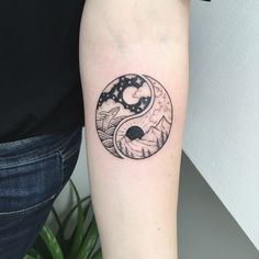 a woman's arm with a black and white yin - yang tattoo on it