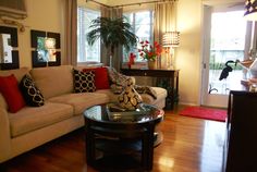 a living room with white couches and red pillows on top of the sofas