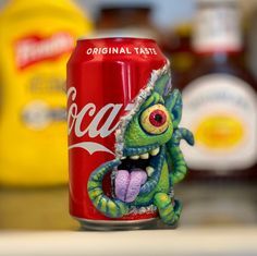 a can of coca - cola with an evil looking creature on it's side