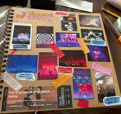 a spiral notebook covered in stickers and photos on top of a table next to a pen