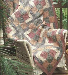 a blanket sitting on top of a chair next to a potted plant