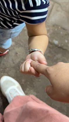 two people holding hands while standing next to each other on the ground in front of one another