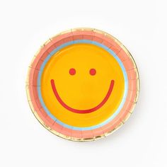 a yellow and pink plate with a smiley face on it's side, against a white background