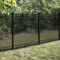 a black metal fence in the middle of some grass