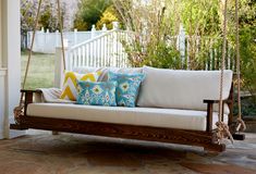 a porch swing with pillows on it