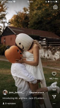 a man and woman dressed up in costume hugging each other with an orange mask on their head