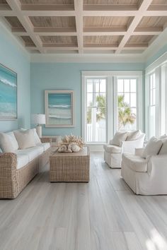 a living room with blue walls and white furniture in front of two large windows that overlook the ocean