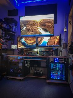 the computer desk has two monitors on it, and is lit up with blue lights