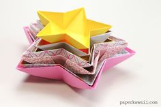 an origami star sitting on top of some folded up pieces of pink paper