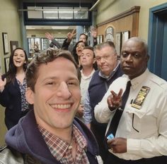 a group of people standing around each other in a hallway with one man smiling at the camera