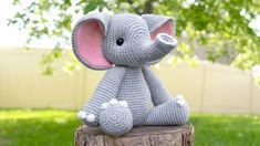 a crocheted elephant sitting on top of a tree stump