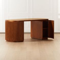 a wooden desk sitting on top of a hard wood floor next to a white wall