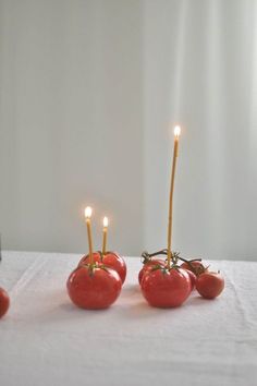 four tomatoes with candles in them sitting on a table