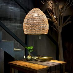 a wooden table with a plant on it and a lamp hanging from the ceiling over it