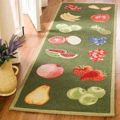 a green runner rug with fruits and vegetables on it in front of a vase filled with flowers