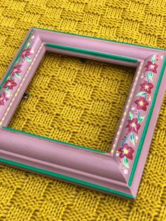 a pink frame sitting on top of a yellow blanket next to a green and white object